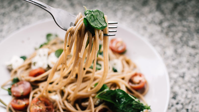 Someone lifting spaghetti from a bowl with a fork