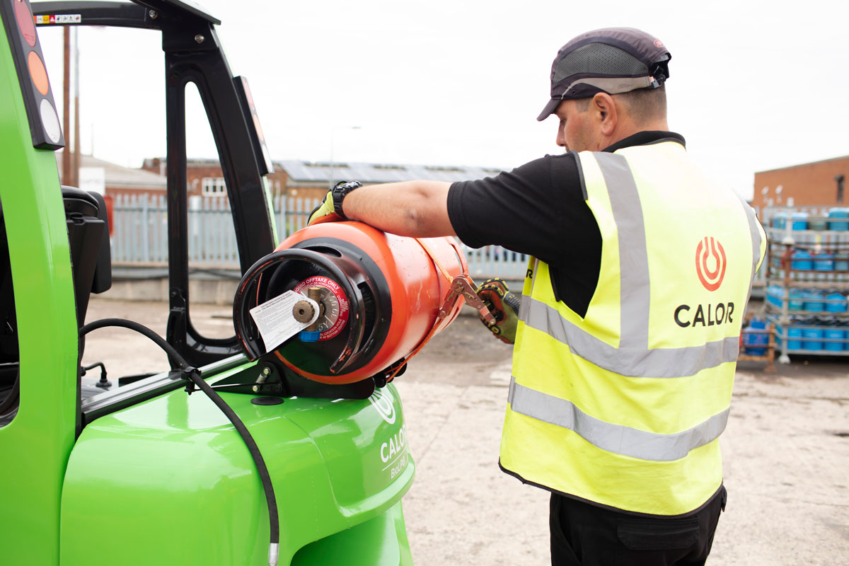 Man securing an Calor gas cylinder to green FLT 