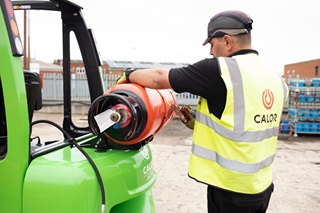 Man securing an Calor gas cylinder to green FLT