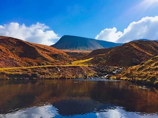 A landscape image of a lake and hills on a sunny day in the UK