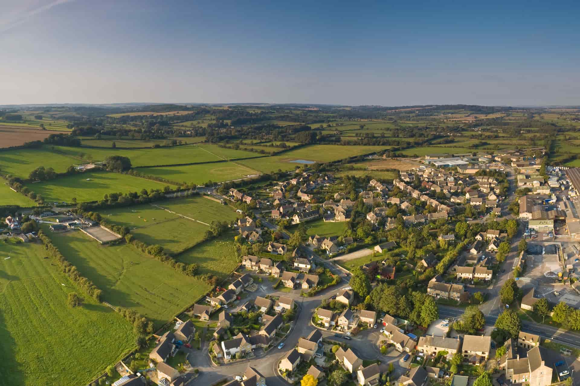 A satalite view of an off grid town in the UK with green fields to the left and blue sky with no clouds