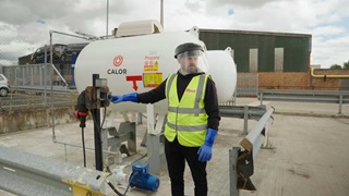 Man in high vis pressing a button next to a Calor LPG tank