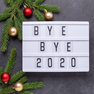 A light box with "bye bye 2020" in letters, baubles and christmas tree brnaches surrounding