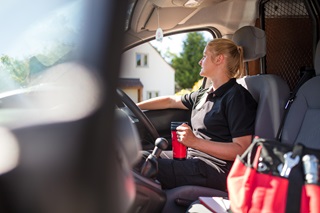 An LPG engineer in a Calor vehicle, looking out of the window with a flask