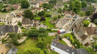 An aerial view of a Calor lorry driving through a rural village