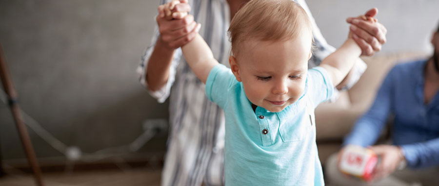 A young toddler walking with his mother